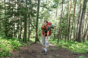 Obraz premium Female tourist with backpack and mat stoped to have a rest in walking in forest
