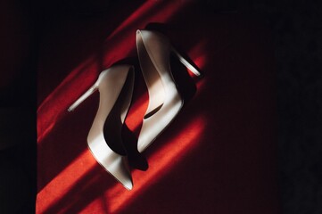 Pair of wedding shoes arranged on a red tablecloth.