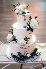 Obraz na płótnie Canvas Elegant white and gold cake adorned with delicate roses.
