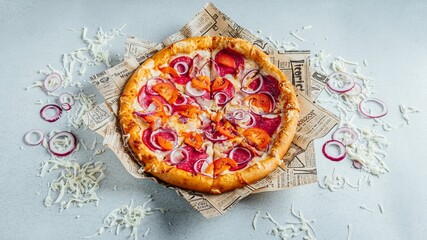 pizza with onions and sauce on newspaper wrapper with shredded cheese