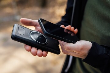 Closeup of the hands of a person holding a smartphone and a wireless phone charger