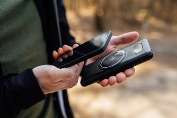 Closeup of the hands of a person holding a smartphone and a wireless phone charger