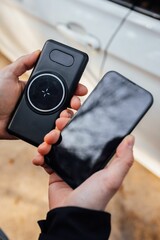 Closeup of the hands of a person holding a smartphone and a wireless phone charger