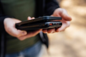 Closeup of the hands of a person holding a smartphone and a wireless phone charger