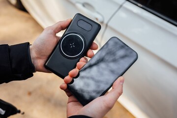 Closeup of the hands of a person holding a smartphone and a wireless phone charger