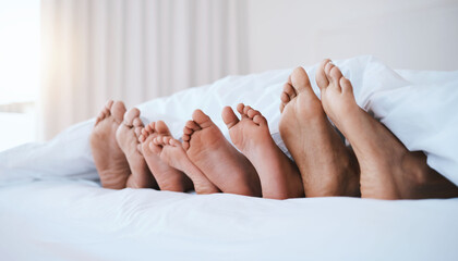 Family, feet in bed and in bedroom of their home with a lens flare sleeping together. Resting or...
