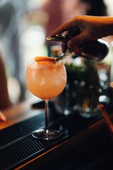 Closeup shot of a bartender pouring a beverage into a cocktail glass on a bar table.