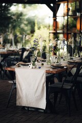 Wedding table set decorated with a selection of tall glass vases containing white flowers.