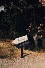 Wooden sign displaying directions to a parking area and a secret garden.