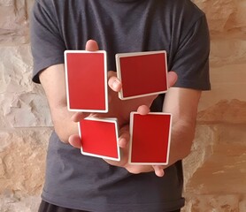 Young man performing a card trick with a deck of red playing cards.