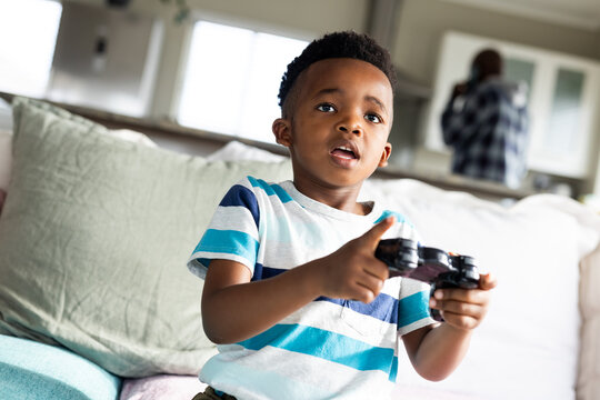 African american boy sitting on sofa and playing video games