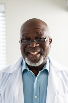 Portrait of happy senior african american male doctor wearing lab coat and glasses