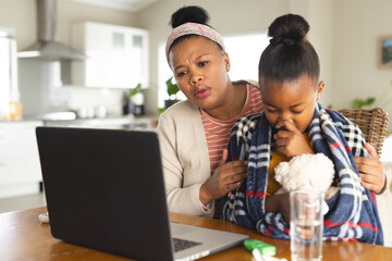 African american mother and daughter using laptop for online consultation with doctor