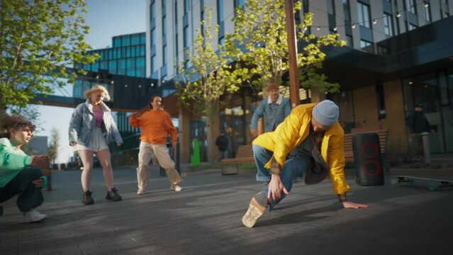 Young And Athletic B-Boy Breakdancing To Break Beats On The City Street Among Modern Buildings In The Circle Of Friends. Fashionable Young People Supporting Dancer, Filming On The Smartphone.