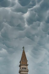 Vertical shot of a historic tower under a cloudy sky in Piran, Slovenia