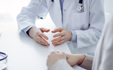 Doctor and patient discussing current health questions while sitting at the table in clinic office,...