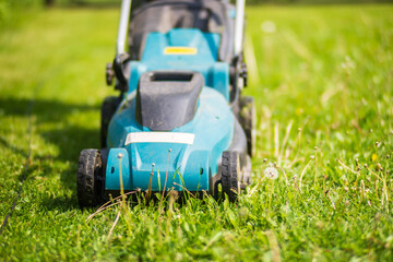 Lawn mover on green grass in modern garden or backyard. Machine for cutting lawns. Gardening care tools and equipment