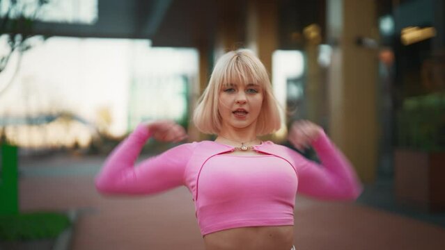 Following Shot Of Beautiful And Fashionable Young Caucasian Woman Wearing Pink Outfit And Voguing On City Street. Vogue Dancer Practicing Arms Performance During The Day. Preparing For The Vogue Ball.