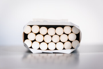 Open pack of cigarettes resting on table, front view, white background.