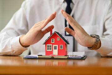 Man hands protecting over little house. Property insurance and security concept