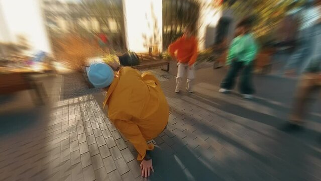 Trendy Zoom Blur Dynamic Edit of Young B-boy Breakdancing On City Street Among Modern Buildings In Urban Area. Group Of Friends Cheering On Background, Supporting Breakdancer Practising Choreography.