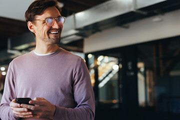 Pensive business man holding a cellphone in a modern workplace