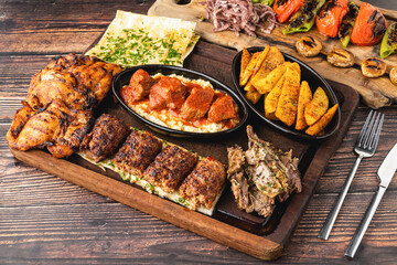 Mixed Turkish grill consisting of adana kebab, grilled chicken and lamb tandoori on wooden table