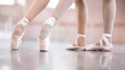 Close-up of the legs of two ballerinas in pointe shoes in a dance class.