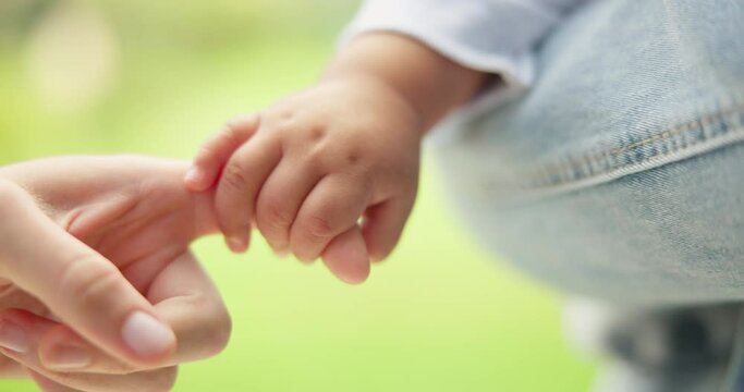 Finger, love and a mother holding hands with her baby outdoor in the garden closeup for trust, care or bonding. Morning, kids or family with a woman and infant child in a backyard together in summer