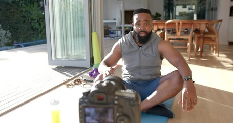 African american male fitness vlogger advicing and filming at home, slow motion