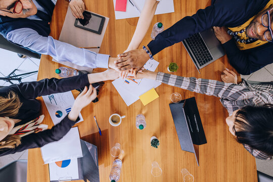 Happy businessmen celebrate success and joy of teamwork in office table photo. Businessmen of different working ages express joyful victory by showing unity and support.