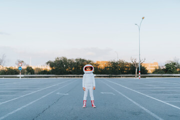 Girl dressed as astronaut standing in parking lot