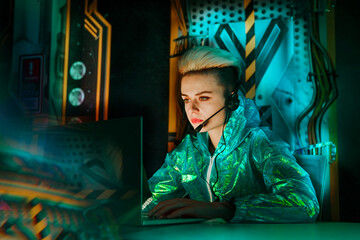 Young gamer wearing headset playing video games on laptop at desk