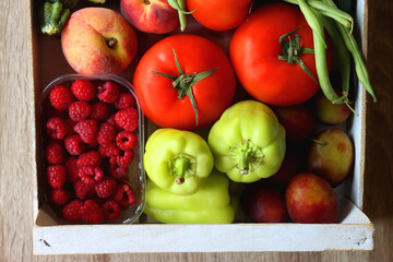 Wooden crate full of healthy seasonal fruit and vegetable. Top view, wooden background.