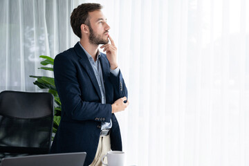 Handsome businessman in black suit stand confidently in his modern office portrait, deep in thought...