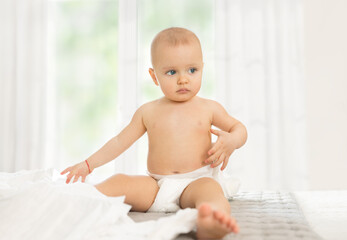 Baby on bed playing with diapers