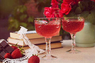 Glasess of red homemade wine. Natural strawberry infusion or shrub. Roses bouquet. Aesthetics summer table settings