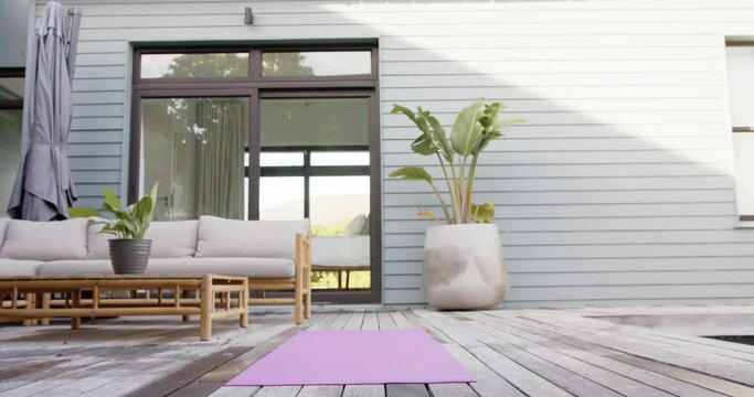 General view of terrace with sofa, plants and yoga mat on floor, slow motion