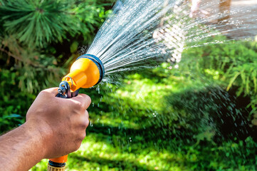Man spraying water from hose in garden