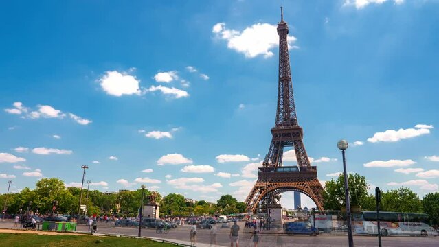 Beautiful Champ de Mars and the Eiffel Tower timelapse on a sunny summer day in Paris, France. Green trees and sunny sky in the capital of France.