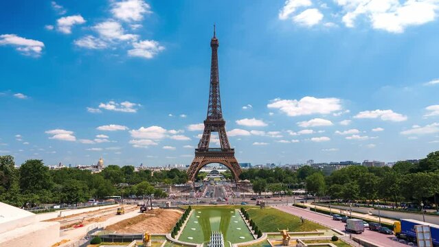 Beautiful Champ de Mars and the Eiffel Tower timelapse on a sunny summer day in Paris, France. Green trees and sunny sky in the capital of France.