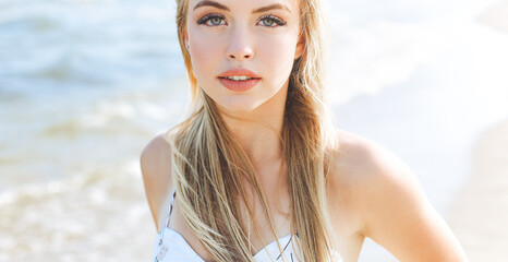 Happy blonde woman in free happiness bliss on ocean beach standing straight and posing