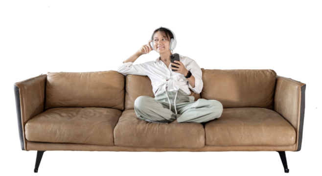 Listening to music playlist with headphones using the app in the phone, sitting on the couch in a white shirt woman. transparent background, png.
