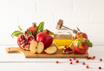 A jar of honey and spindle on a wooden board with ripe fruits, pomegranates and apples. traditional food for the holiday of Rosh Hashanah. front view.