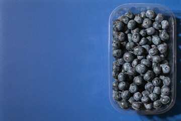 Blueberries on a blue background. Top view, copy space.