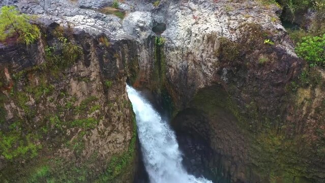 Vuelo de drone sobre una cascada que forma un r&iacute;o con agua de color turqueza.