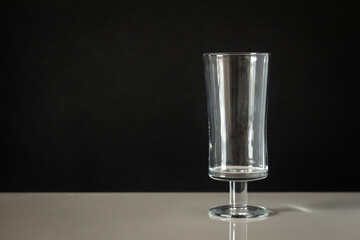 glass beaker on a leg with a black background on a white table