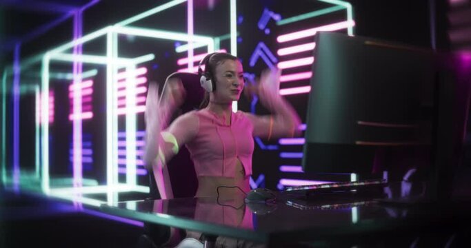 Internet Streamer Making a Live Video Game Broadcast on Social Media Channels. Beautiful Girl Using a Desktop Computer in a Room with Futuristic Neon Background. Gamer Winning and Celebrating