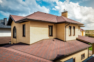 Modern roof with new roof shingles under cloudy sky