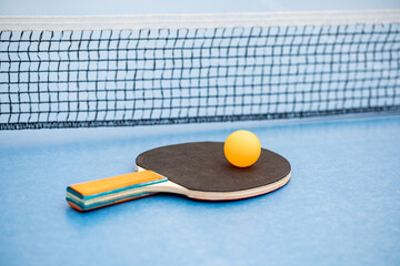 Table tennis. Blue ping pong table. Ping pong racket and ball. The concept of sport and healthy...